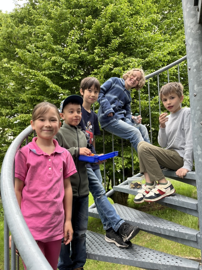 Kinder sitzen auf einer Wendeltreppe